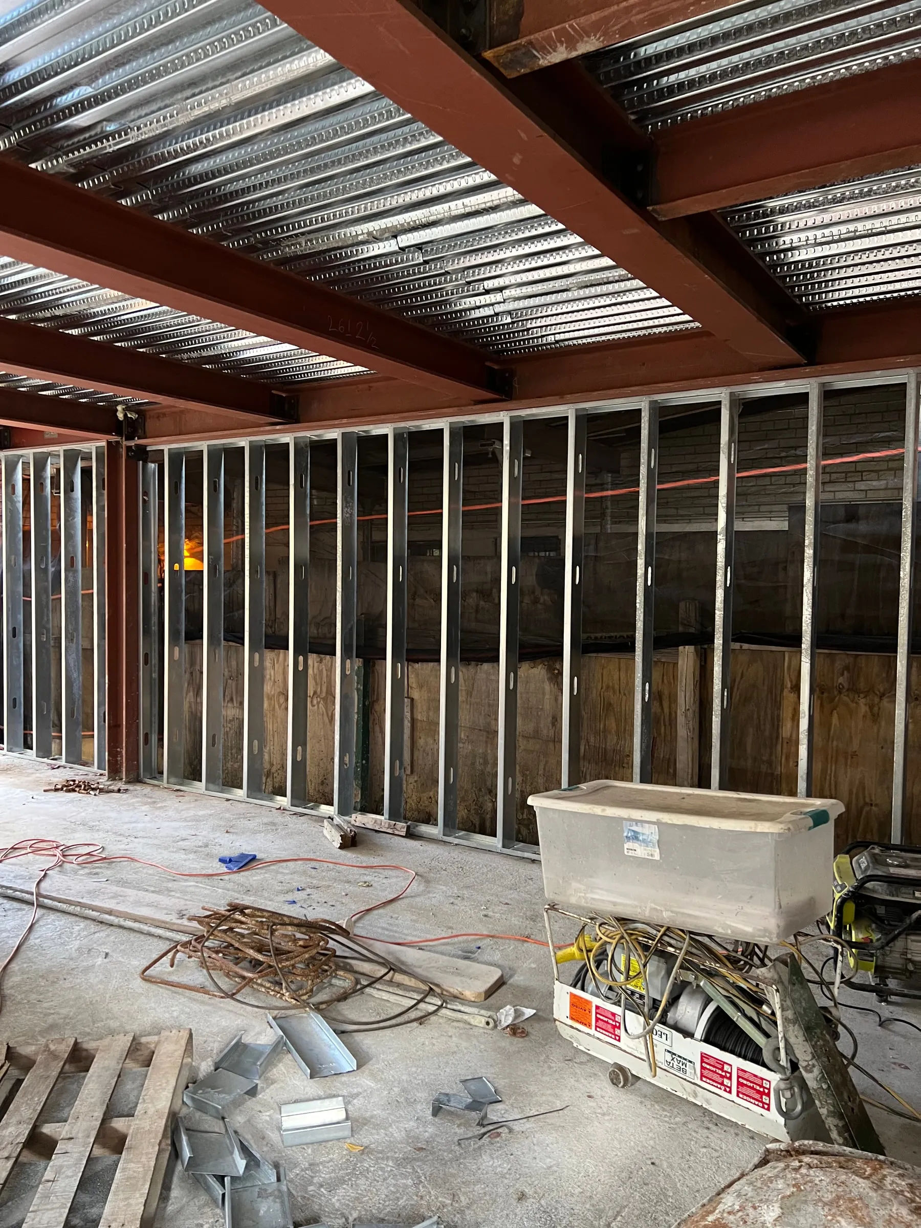 Steel beams and composite deck overhead, partitions set out on the slab below.