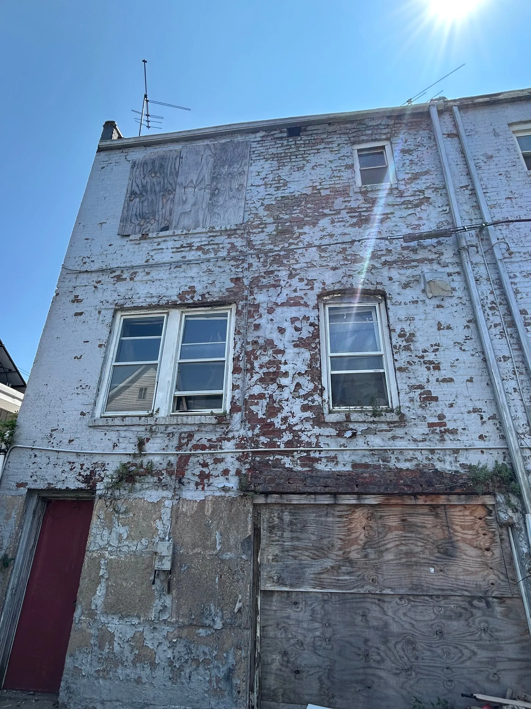 The rear elevation with the render gone and the openings boarded over.