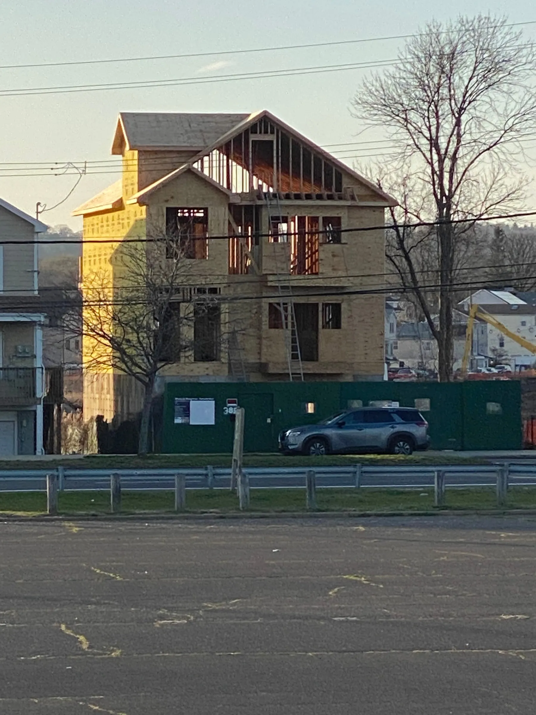 Roof and dormers framed out, seen from across the road at the end of a day.