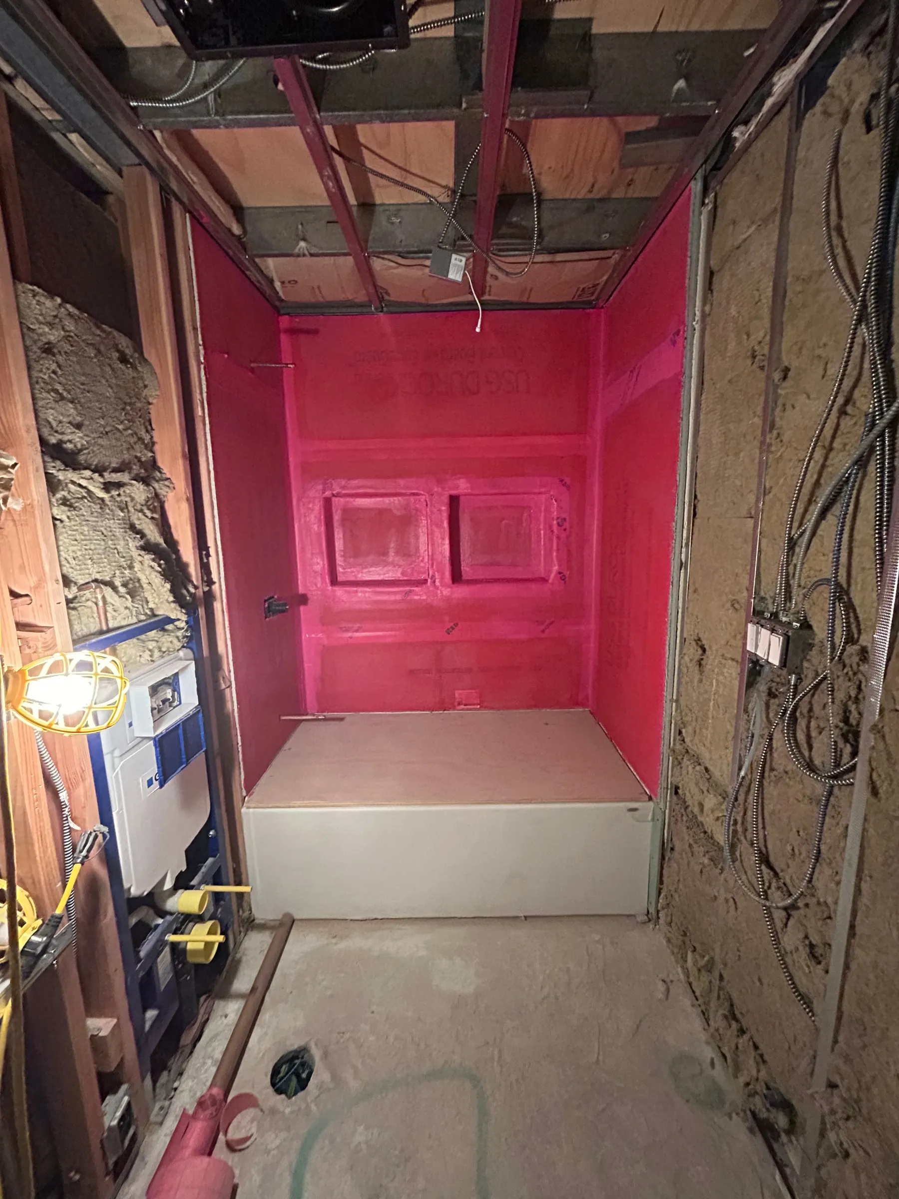 Bathroom rough-in, with the shower base formed and waterproofed ahead of tile.